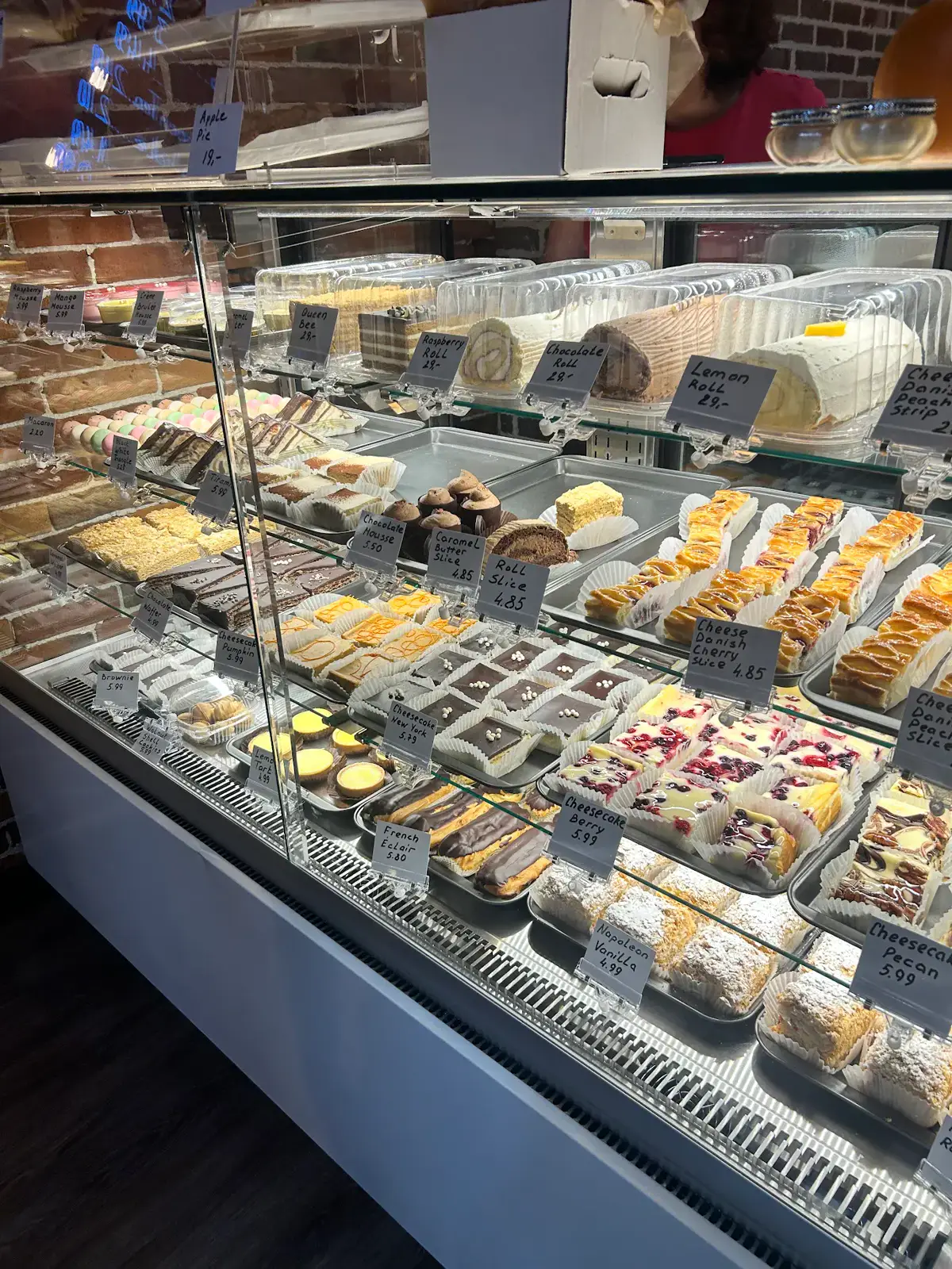 The display case packed with tortes, cheesecakes, rolls and Danish slices